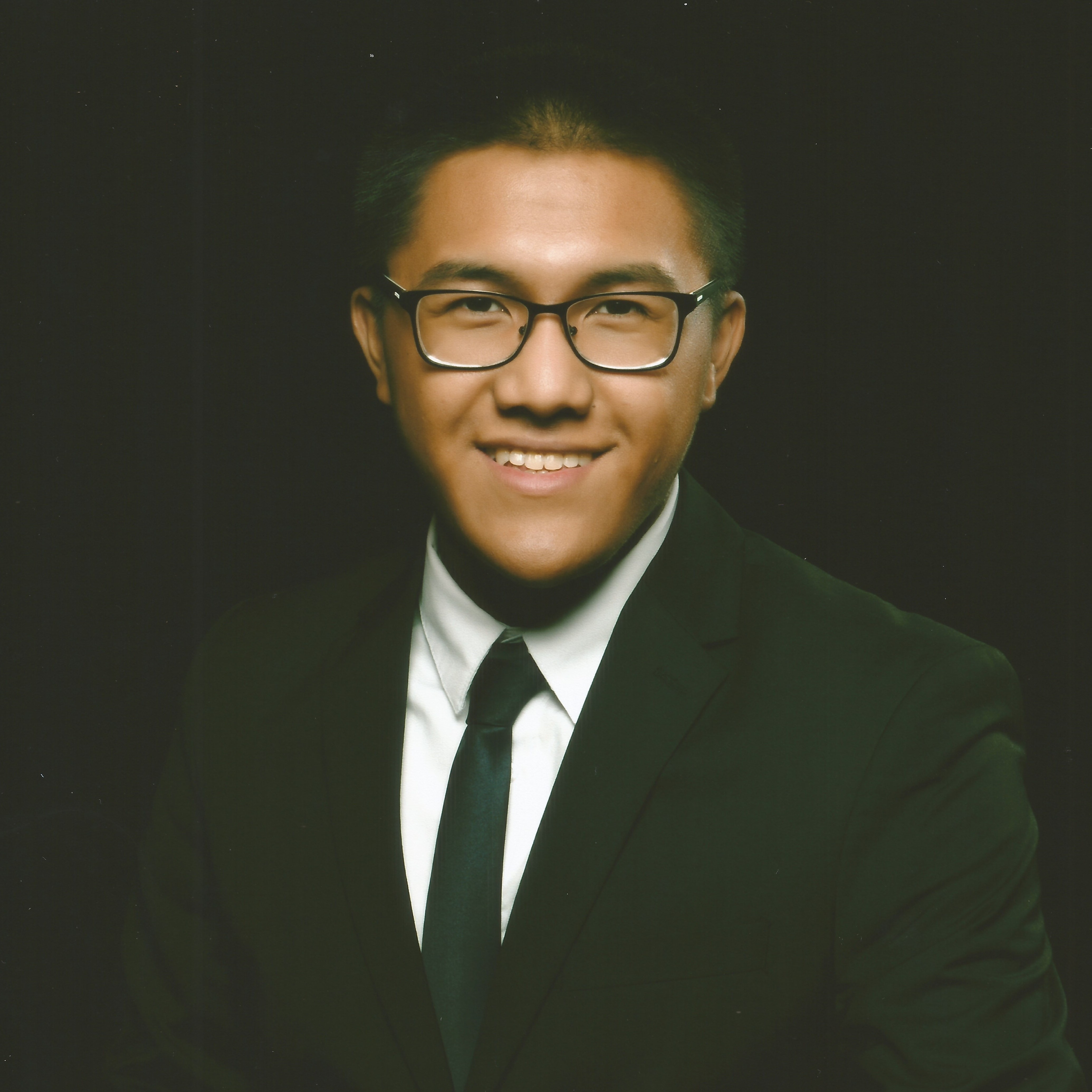 A person wearing a suit and glasses who is smiling at the camera.